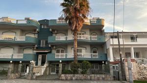 a building with a palm tree in front of it at Complex Summer Memories Souzan in Keramoti