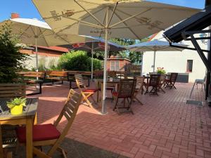 eine Terrasse mit Tischen, Stühlen und Sonnenschirmen in der Unterkunft Restaurant und Pension Zur Wildgans in Arendsee + 22 Fotos