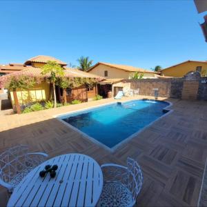 a pool with chairs and a table in front of a house at Cakau House - espaço amplo e aconchegante in Maricá