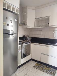 a kitchen with white cabinets and a stainless steel refrigerator at Apto Amplo 3 quartos com lazer e bem localizado in Aracaju