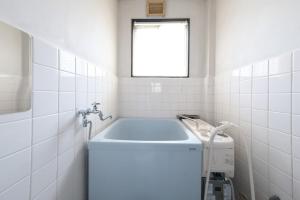 a white tiled bathroom with a sink and a window at KEI HOUSE Yamato 101 in Yamato +42 photos