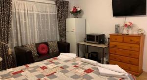a bedroom with a bed and a dresser and a refrigerator at Deluxe Queen Room in Perth