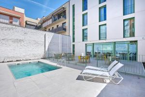 a patio with a pool and a chair and a building at Hostelfly Fira Barcelona in Hospitalet de Llobregat