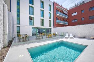 a swimming pool in front of a building at Hostelfly Fira Barcelona in Hospitalet de Llobregat