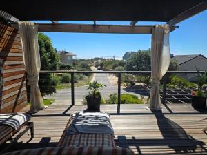 a porch with two chairs and a view of a street at 82 Steps to the Beach in Pringle Bay