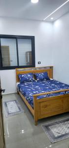 a bedroom with a wooden bed with blue sheets at Maison salakta in Ksour Essaf