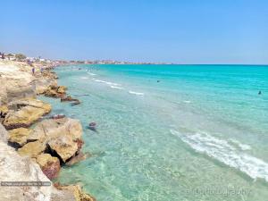 a beach with people swimming in the water at Maison salakta in Ksour Essaf