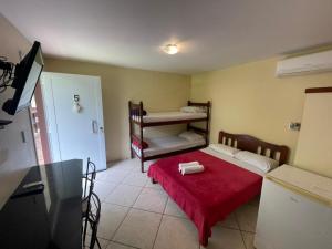 a small room with a bed with a red blanket at Flat Salto Dagua Penedo in Penedo