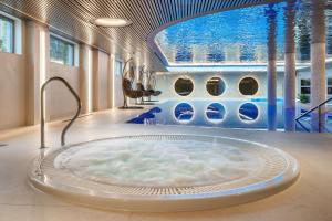 a large bath tub in a room with a pool at Hotel Haffner Resort & Spa - Destigo Hotels in Sopot