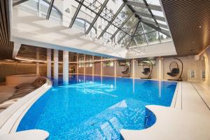 a large swimming pool with blue water in a building at Hotel Haffner Resort & Spa - Destigo Hotels in Sopot