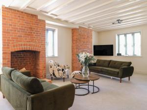 a living room with two couches and a brick wall at Gardeners Cottage in Oakham