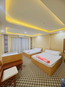 a room with three beds and a yellow ceiling at Shrestha Hotel And Lodge in Dhāding