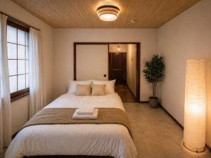 a bedroom with a large bed and a potted plant at TOMOSHIBI Kurashiki Zen House Near Bikan Historical Quarter 美観地区近く 和モダン一棟貸し in Kurashiki
