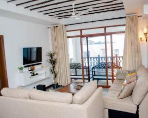 a living room with two white couches and a television at WakaWaka SeaView Beach Condo in Mombasa