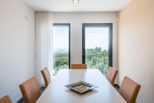 a dining room with a table with chairs and two windows at Villa Monchique in Monchique