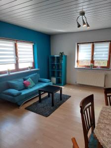 a living room with a blue couch and a table at Ferienwohnung am Stiefel in Sankt Ingbert +2 photos