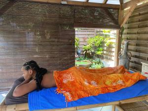 a woman laying on a bed with a blanket at Studio Zen Caza Form -Option Spa Sauna au jardin in Le Lamentin