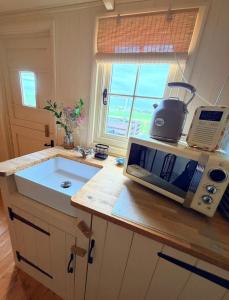 a kitchen with a toaster and a microwave on a counter at Coorie and Keek Shepherd's Hut in Prestrie +15 photos