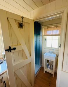 a bathroom with a barn door and a sink at Coorie and Keek Shepherd's Hut in Prestrie