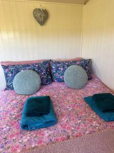 a bed with two cushions and two pillows on it at Coorie and Keek Shepherd's Hut in Prestrie