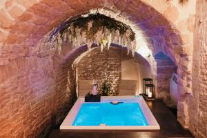 a bath tub in a brick walled room with a pool at Moira Suite in Bitonto