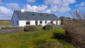 a white house on top of a green field at Little Tara, Ballyconneely in Ballyconneely