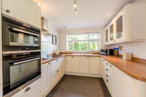 a kitchen with white cabinets and a large window at 4 Bed in Bideford oc-76452 in Parkham