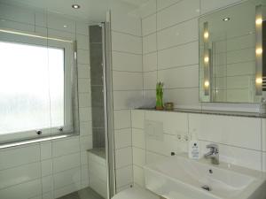 a white bathroom with a sink and a mirror at Das LENNI in Büren