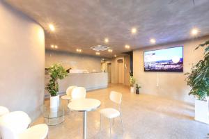 une salle de réunion avec des chaises blanches et une télévision à écran plat dans l'établissement Stay Libera, à Gangneung