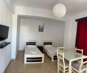 a room with two beds and a table and a dining room at Hotel Villa Ruci in Ksamil