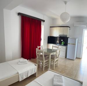 a room with a table and a kitchen with a red curtain at Hotel Villa Ruci in Ksamil