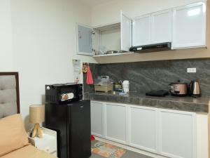 a kitchen with white cabinets and a black refrigerator at Axc cozy inn in Olongapo +3 photos