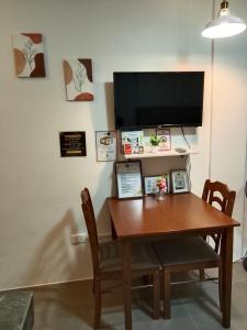 a wooden table with two chairs and a television on a wall at Axc cozy inn in Olongapo