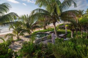 a resort with a pool and palm trees on the beach at Playa Esperanza Tulum in Tulum