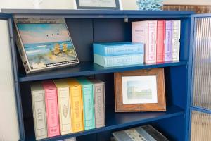 a blue book shelf filled with books and pictures at Surf Side Hotel in Nags Head