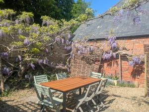 a wooden table and chairs in front of a brick building at South Cotswolds cottage in Great Somerford