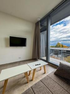 a living room with a table and a large window at Simple Aparts in El Calafate
