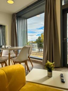 a living room with a yellow couch and a large window at Simple Aparts in El Calafate