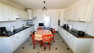 a kitchen with white cabinets and a table and chairs at Gîte Champgrand in Loriol-sur-Drôme