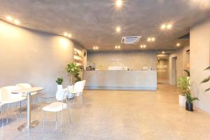 un hall d'entrée avec des tables, des chaises blanches et un comptoir dans l'établissement Stay Libera, à Gangneung