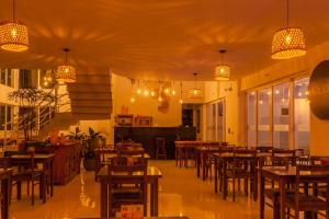 a restaurant with wooden tables and chairs and lights at Almaê Pousada in Matinhos
