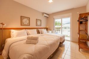 two beds in a room with a large window at Almaê Pousada in Matinhos +83 photos