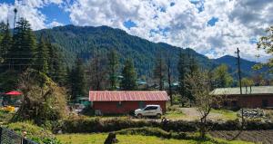a truck parked in front of a barn with a mountain at Barot Palace in Barot 