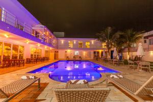 a swimming pool at night with chairs and tables at Almaê Pousada in Matinhos