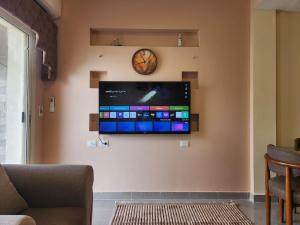 a flat screen tv on a wall with a clock at Modern 3-BR gated Sheikh Zayed Compound Open Views in Sheikh Zayed
