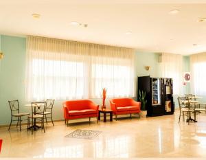 a waiting room with red chairs and tables in a building at Hotel Anita B&B sul lungomare in Gatteo a Mare