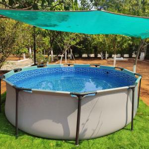 a hot tub in the grass with a blue canopy at OrchardNest in Moinabad