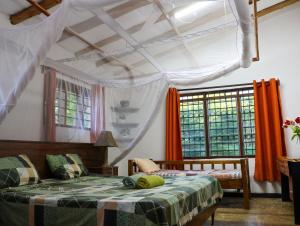 a bedroom with a bed and windows with orange curtains at Tradewinds Lodge in Diani Beach +161 photos