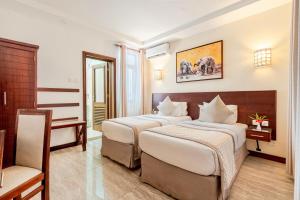 a hotel room with two beds and a desk at PrideInn Hotel Diani in Diani Beach +23 photos