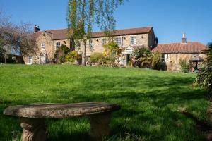 a stone bench sitting in the grass in front of a house at Asquith Hall Hotel & Spa Scarborough in Scarborough